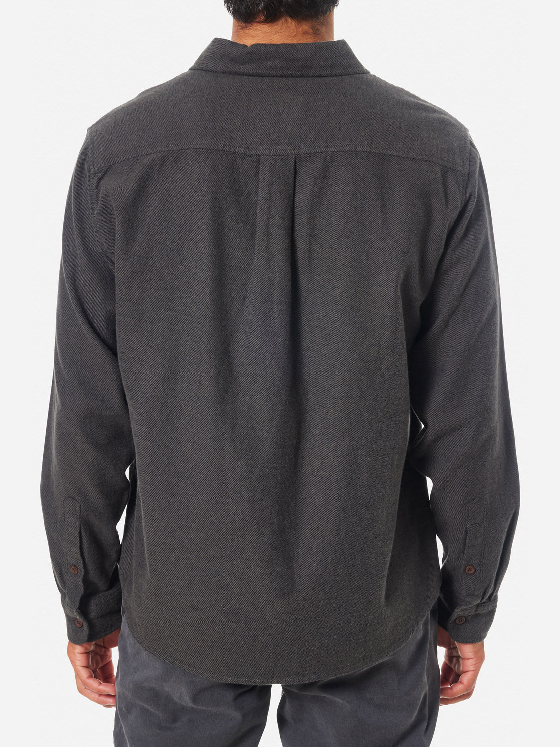 A person wearing a Katin Twiller Flannel Button Down Shirt in dark gray, featuring long sleeves, a collar, and buttoned cuffs, faces away from the camera against a white background. The shirt seamlessly pairs with matching dark gray pants.