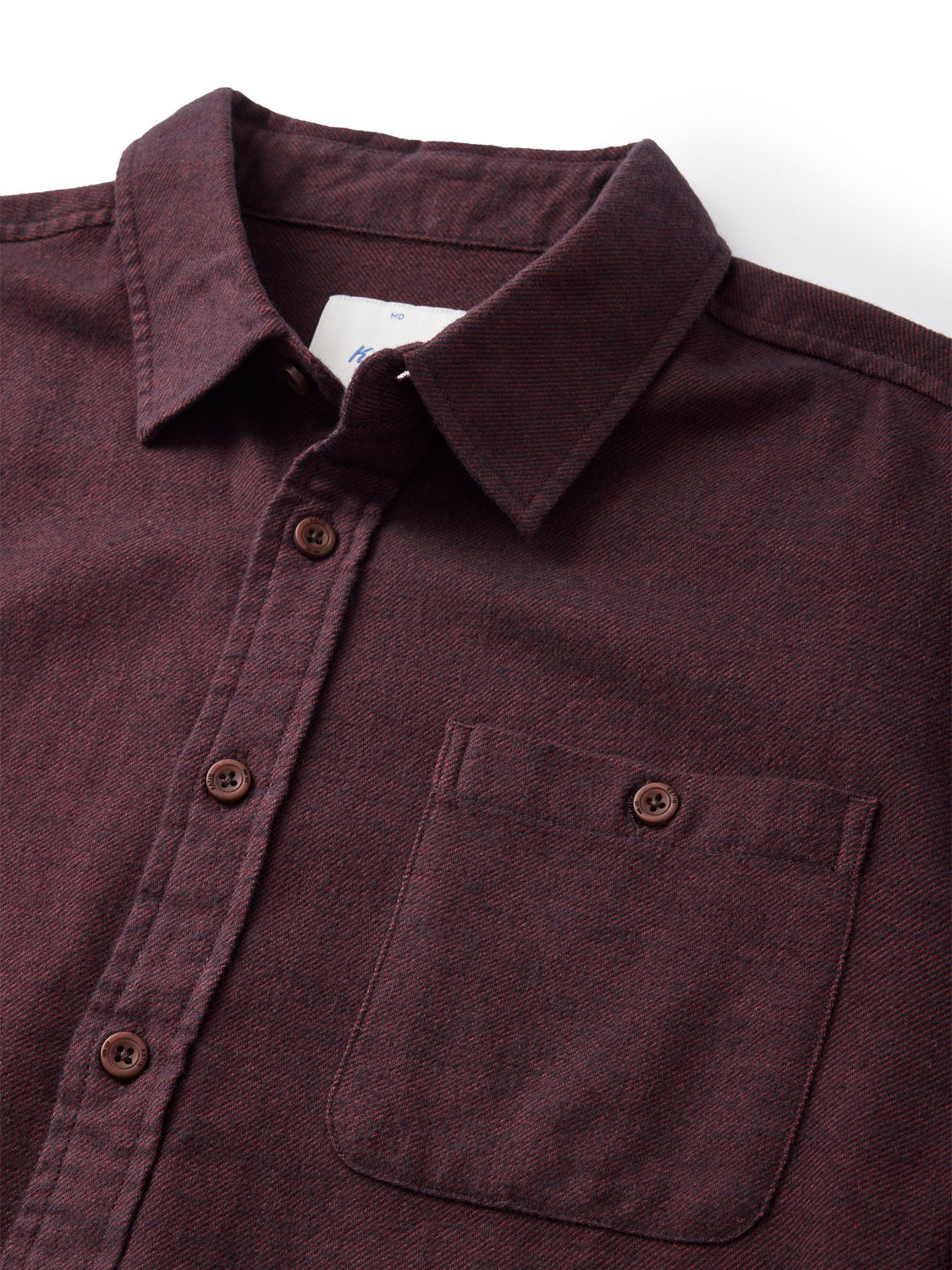 Close-up of the Katin Twiller Flannel Button Down Shirt in dark maroon, showcasing its collar, long sleeves, and chest pocket. Made from textured cotton flannel with dark brown buttons, this piece exudes subtle elegance against a plain white background.