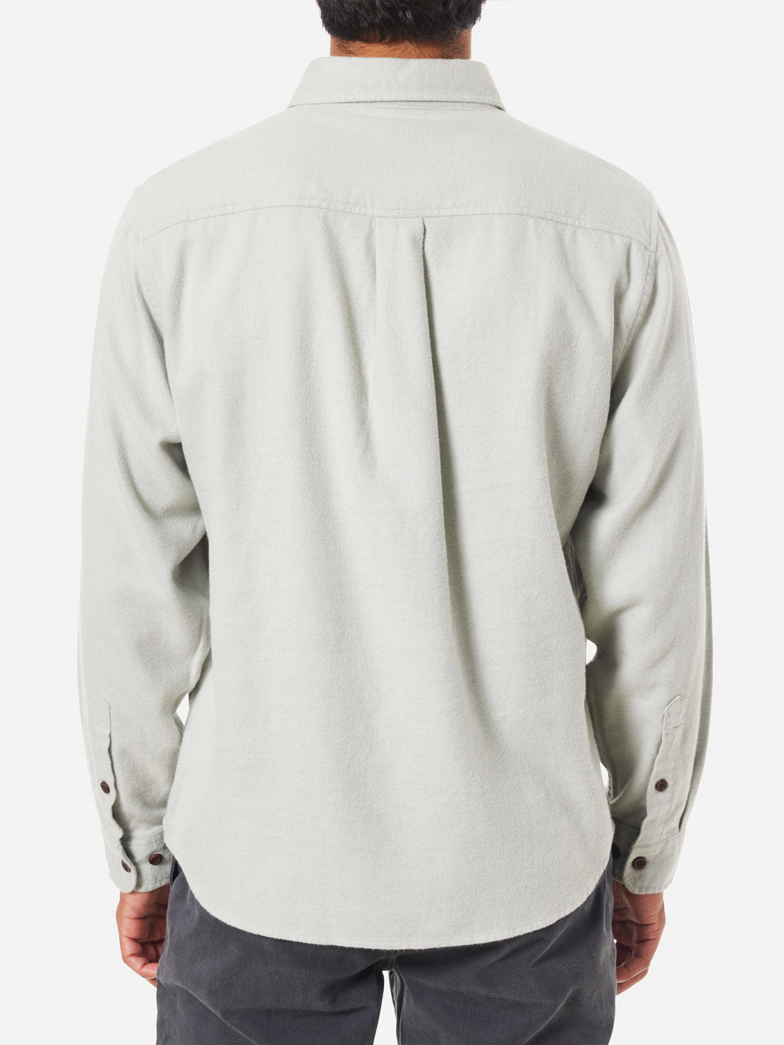 View from the back of a person in an untucked Katin Twiller Flannel Button Down Shirt, featuring buttoned cuffs and moleskin finish. The light gray shirt is worn against a plain white background, showing only the upper back and arms.