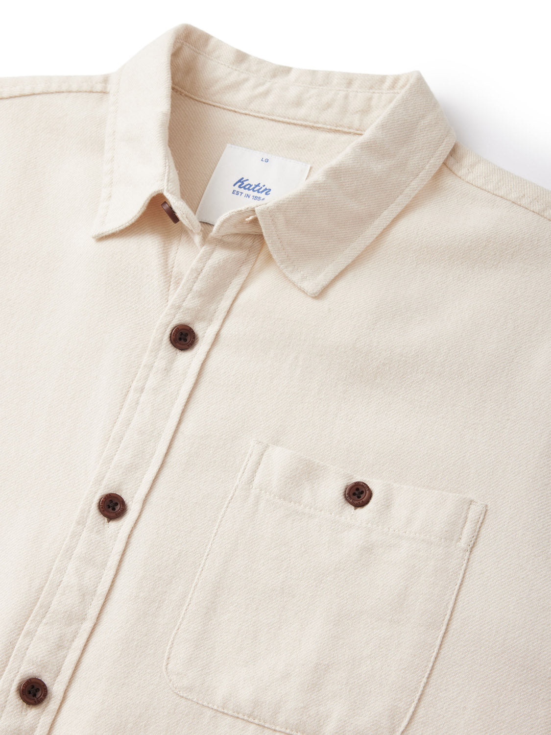 Close-up of the Katin Twiller Flannel Button Down Shirt in beige cotton flannel. It has a collar, single chest pocket, dark brown buttons, and a small tag near the collar. The fabrics slightly textured look adds to its cozy charm.