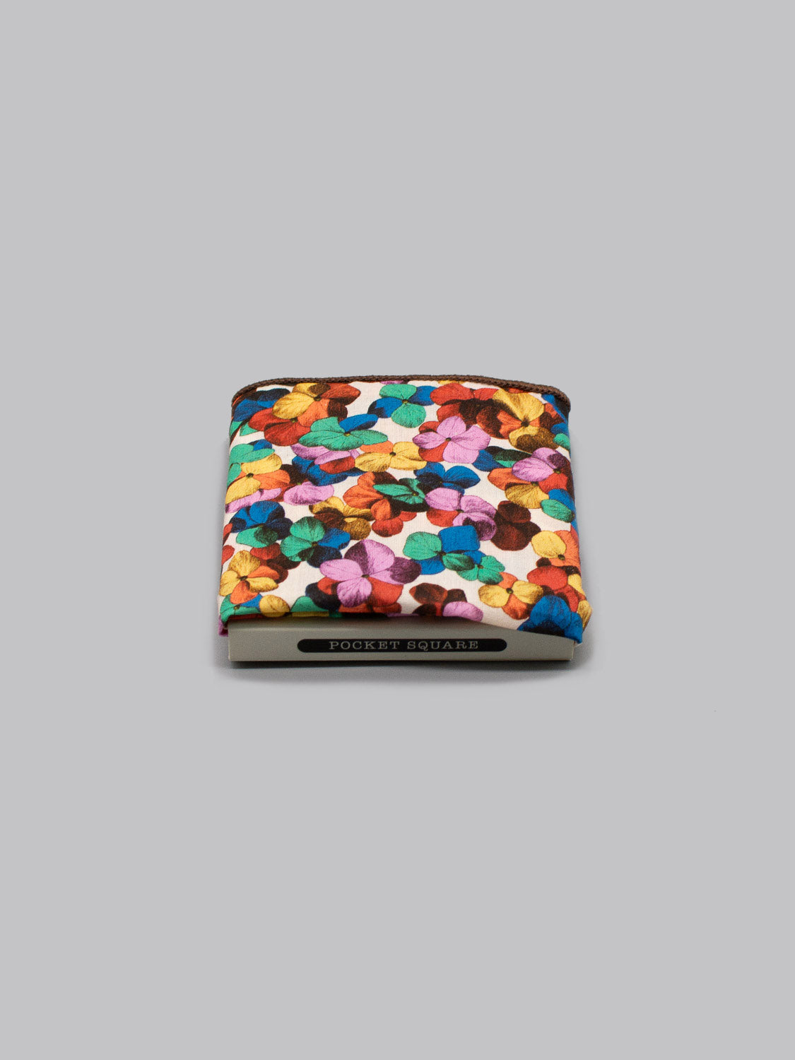 The ID Menswear Liberty™ Hilary Pocket Square, featuring a vibrant multicolored floral pattern, is neatly folded against a plain gray background.