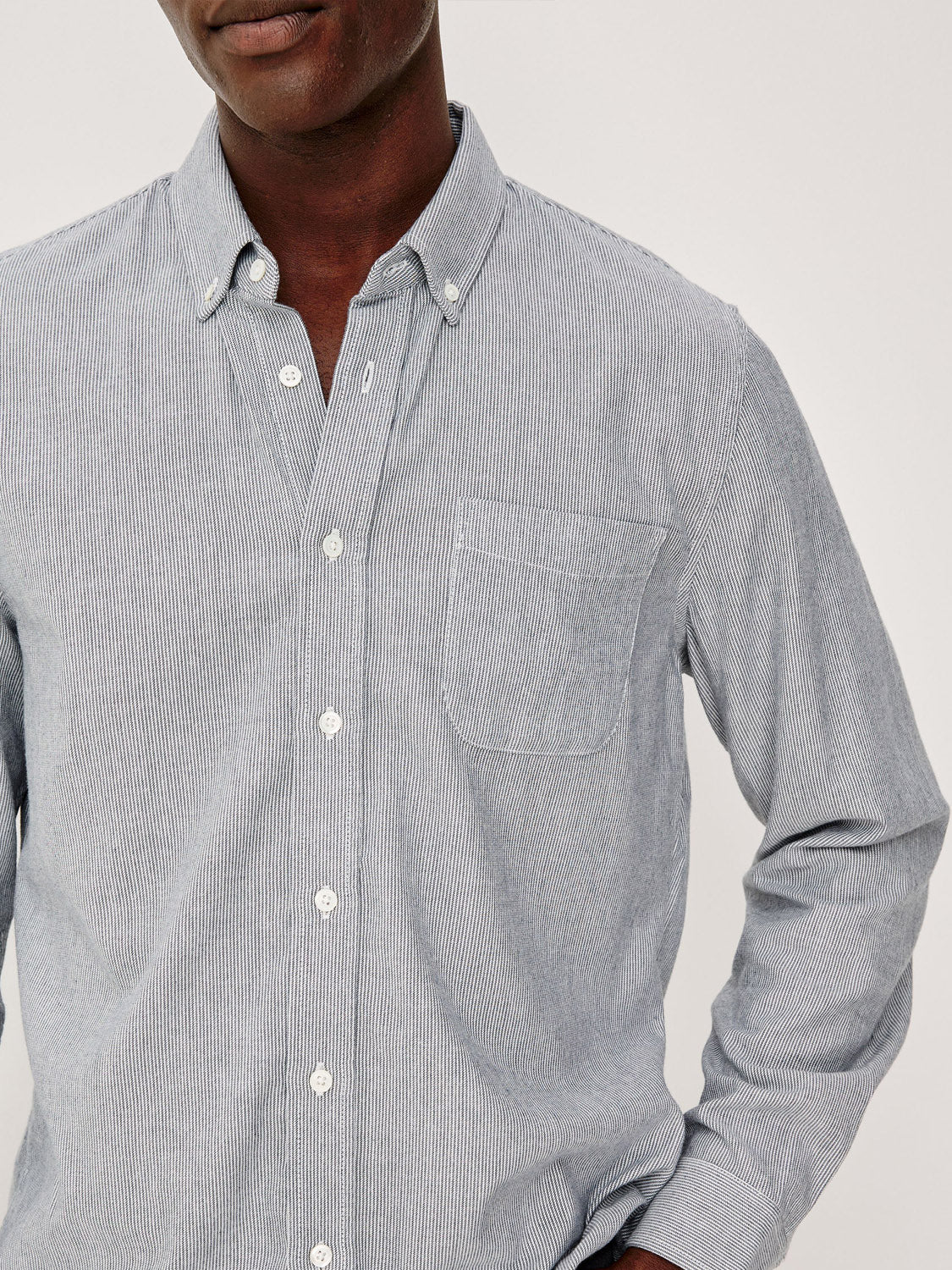 A person wearing the Rails Vance Shirt, a light blue and white striped cotton-twill button-up with a chest pocket, ideal for everyday wear, stands against a plain background. The person’s face is partially out of frame.