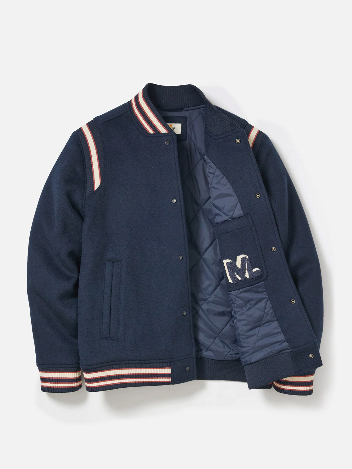 The Fields Wool Varsity Jacket by Marine Layer features navy wool, striped ribbed cuffs, collar, and hem in white, red, and blue, a quilted lining, interior pocket, and a white "M" letter patch. Classic fit and stylishly designed.