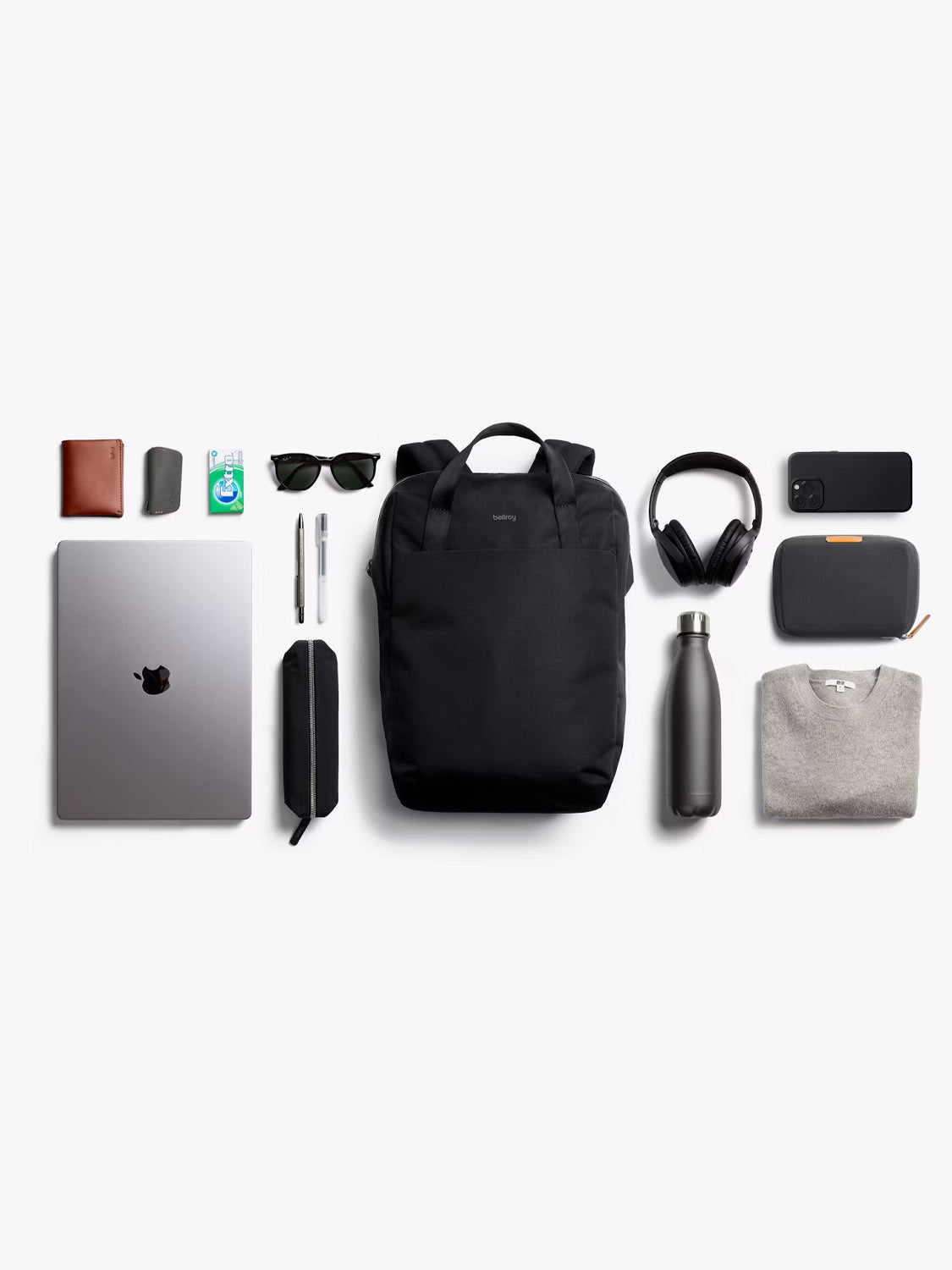 A neatly arranged flat lay displays everyday essentials with the Bellroy Via Workpack - 18L, including a sweater, headphones, water bottle, wallet, sunglasses, phone, pens, gum, keys & pencil case—ideal for a commuter setup.