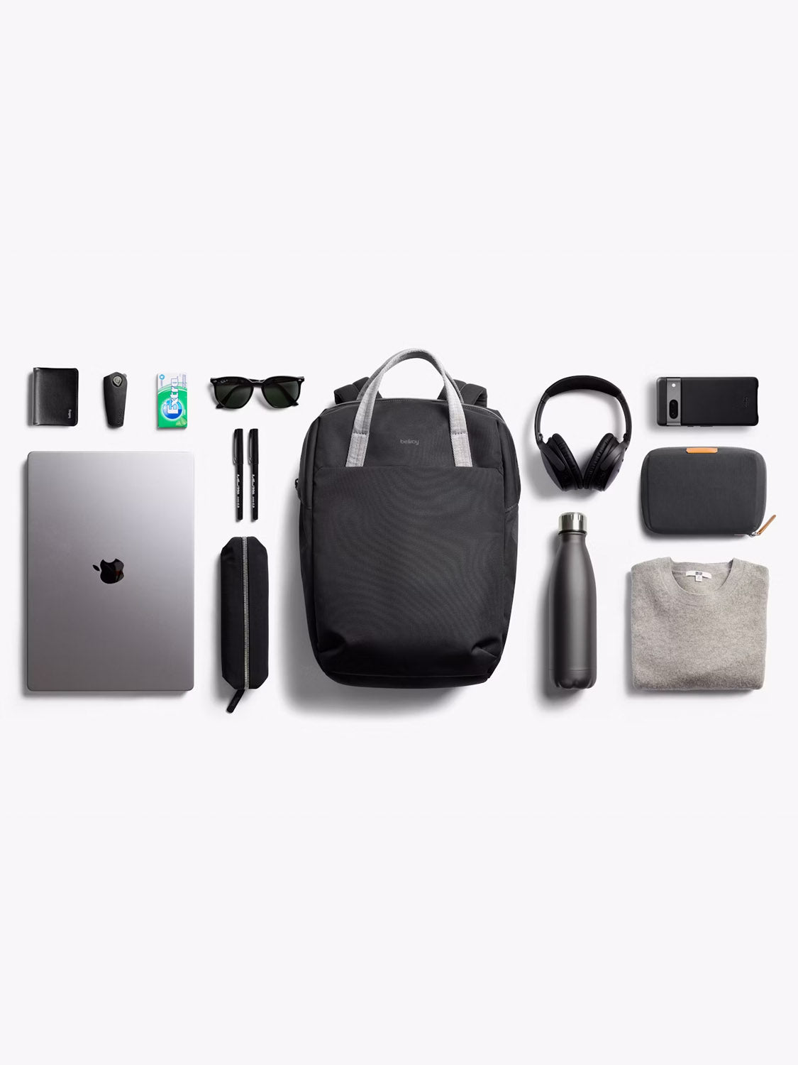 A flat lay of everyday essentials—including the Bellroy Via Workpack - 18L, headphones, water bottle, sweater, sunglasses, pens, wallet, gum, phone, charging cable, and pouches—neatly arranged on a white background.