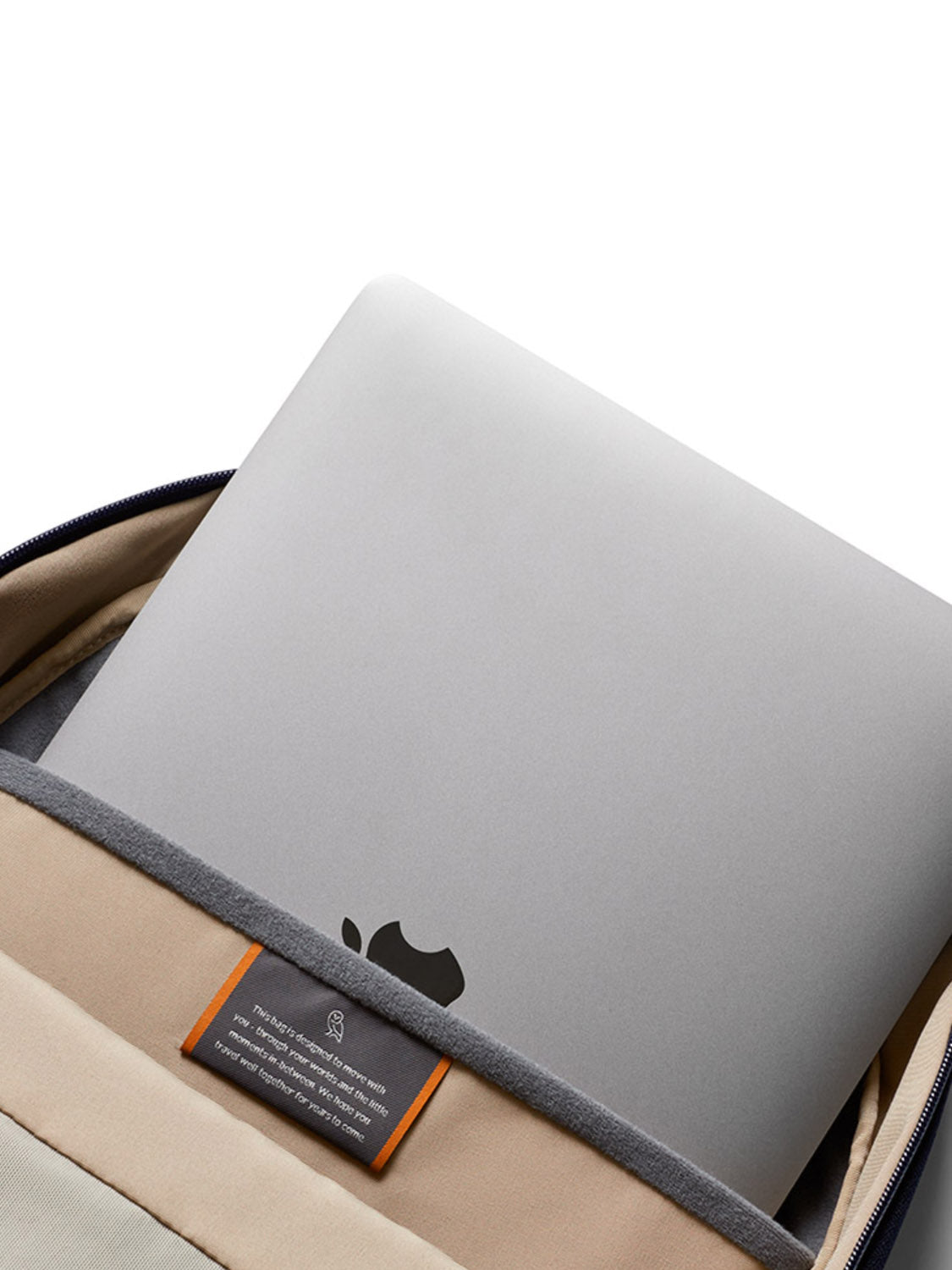 A silver laptop with an Apple logo is placed in the padded compartment of the Bellroy Via Backpack - 20L, a minimalist bag crafted from recycled fabric.