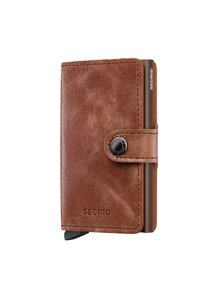 The Secrid Miniwallet Vintage Leather is a compact brown RFID wallet with a snap button closure, embossed brand name, and visible metallic edge, offering a minimalist and stylish design.
