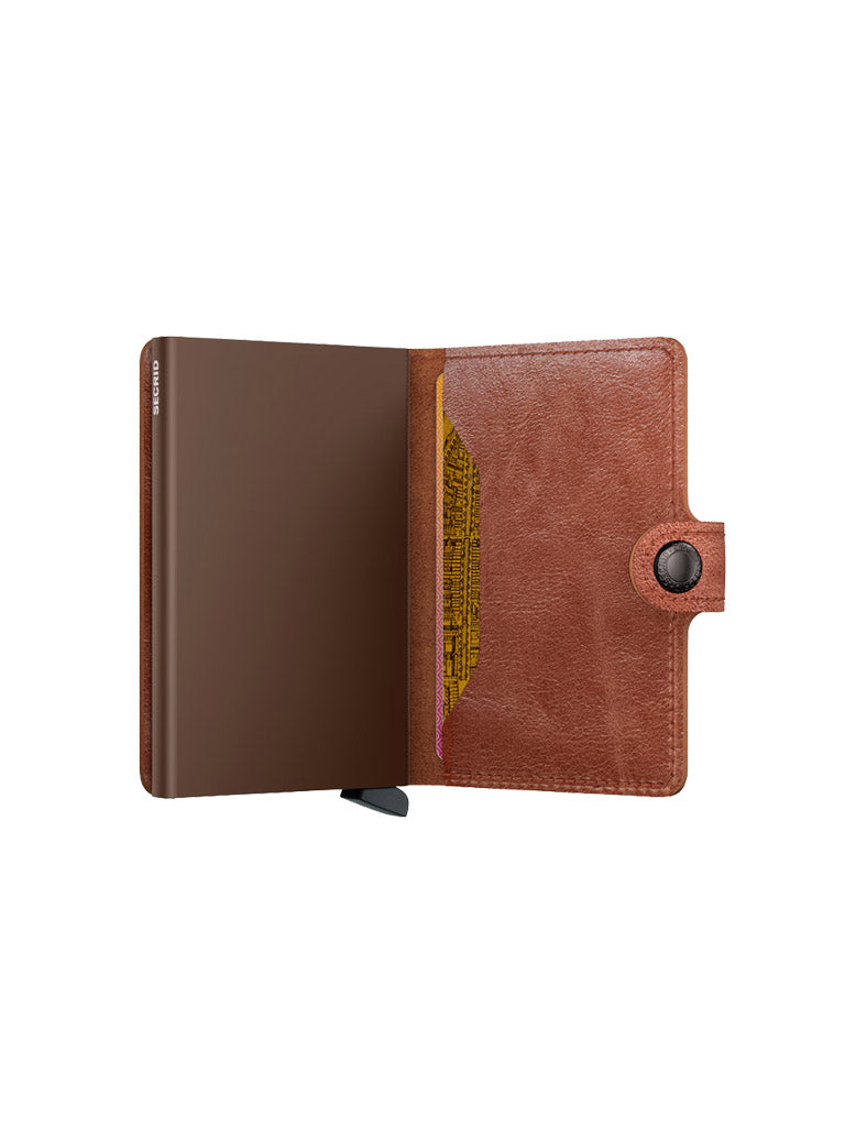The Secrid Miniwallet Vintage Leather features an open design with a snap button, showing a plain brown interior and a yellow paper peeking from the side pocket.