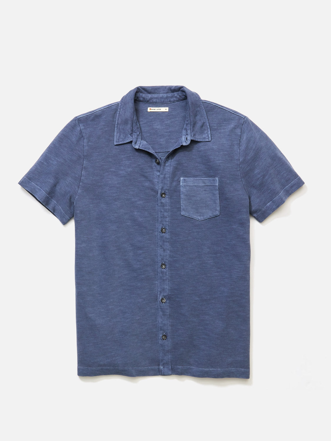 Marine Layers Vintage Heavy Slub Button Down features a short-sleeve design in garment-dyed faded blue, complete with a single chest pocket, all showcased against a white background.