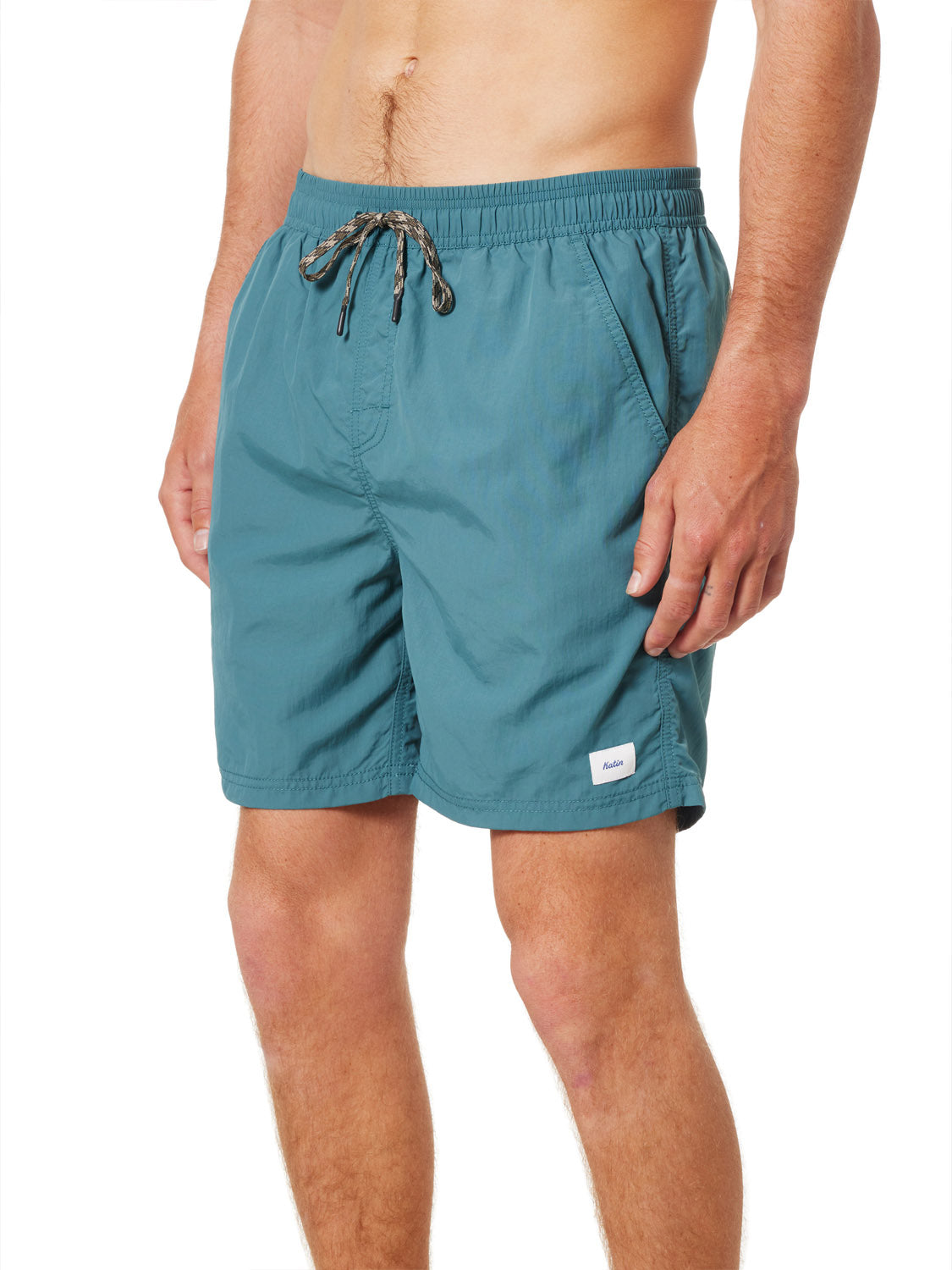 A man stands against a white background wearing Katin Poolside Volley swim trunks with an elastic waistband, mesh brief lining, side pockets, and a small white Katin label near the hem.