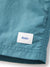 Close-up of Katin Poolside Volley shorts in teal, featuring an elastic waistband and a white sewn-on label by the hem with “Katin” in blue script.