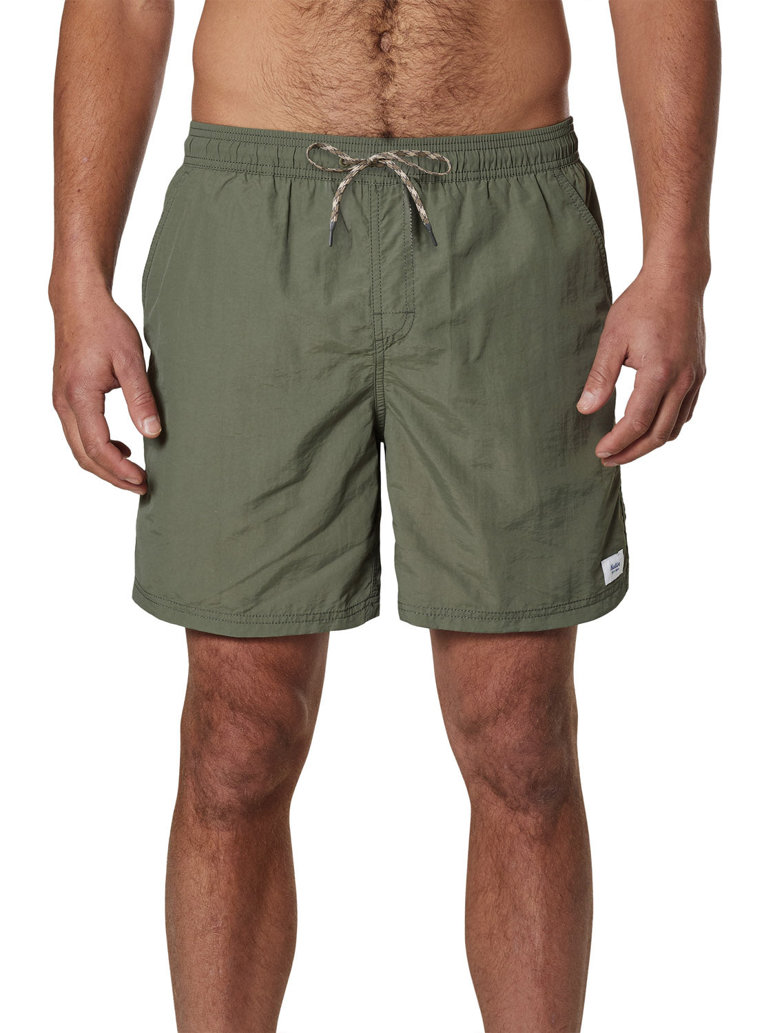 A person wears Katin Poolside Volley nylon shorts in olive green, with an elastic waistband, drawstring, side pockets, and a small white tag on the left leg. Their arms are relaxed at their sides.
