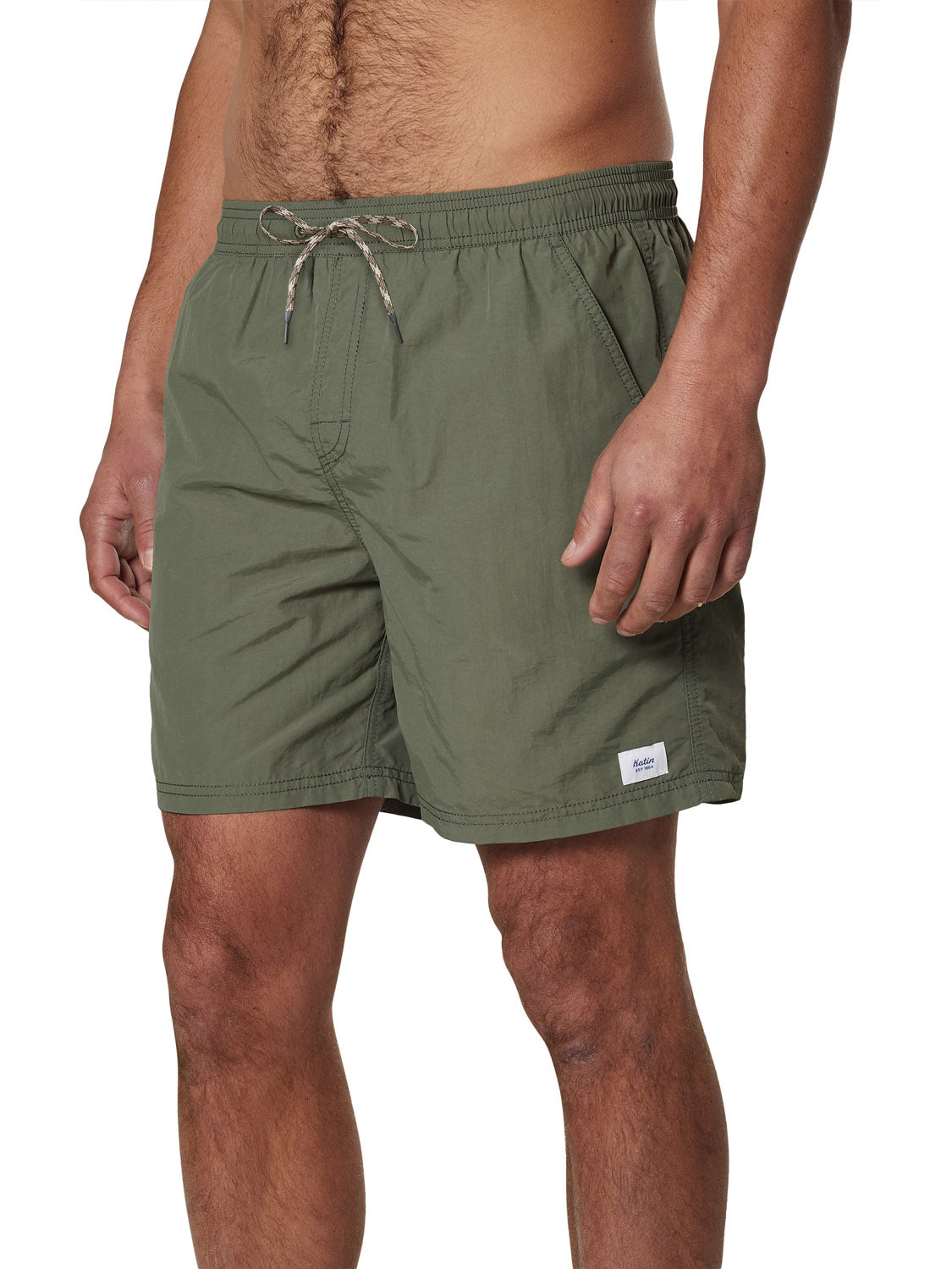 A man wears Katin Poolside Volley olive green nylon shorts with an elastic waistband and a small white label near the hem, shown from mid-torso to mid-thigh against a white background.