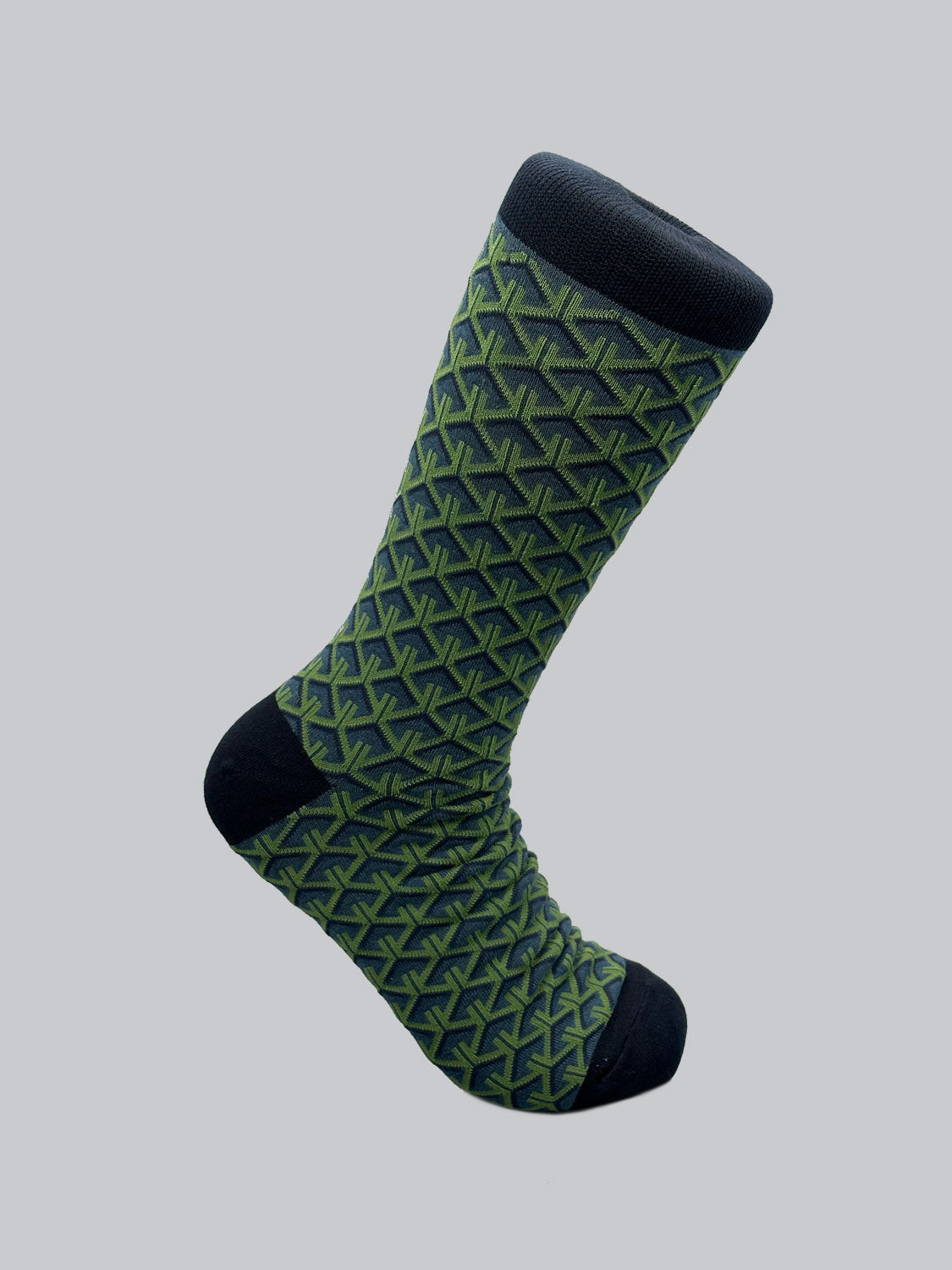 The Wagara Graphic Socks by ID Menswear showcase a single sock with geometric green and black interlocking shapes on a light background, complemented by solid black toe, heel, and cuff, highlighting intricate Japanese designs.