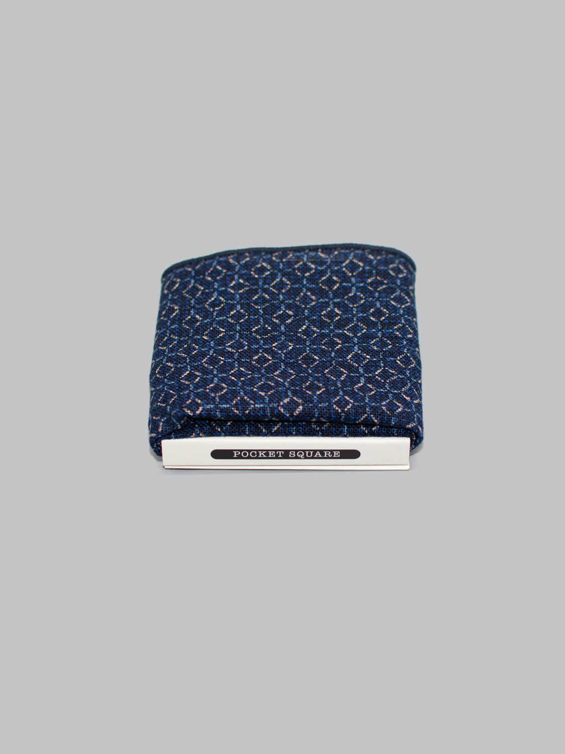 A folded blue Web Pocket Square by ID Menswear, handmade in Brooklyn from 100% cotton, with a metal clip labeled Pocket Square, displayed on a plain gray background.