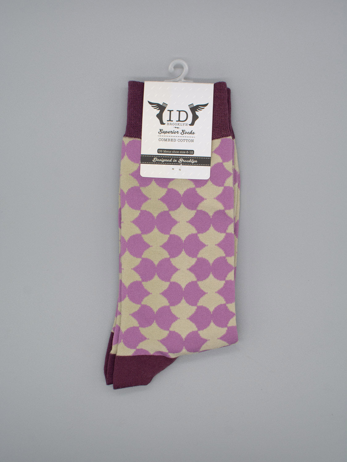 The Wiggle Graphic Socks by ID Menswear feature a cream base with a purple geometric pattern, burgundy cuffs, toes, and heels, crafted from premium combed cotton. Shown on a gray background with an attached black and white ID brand tag.