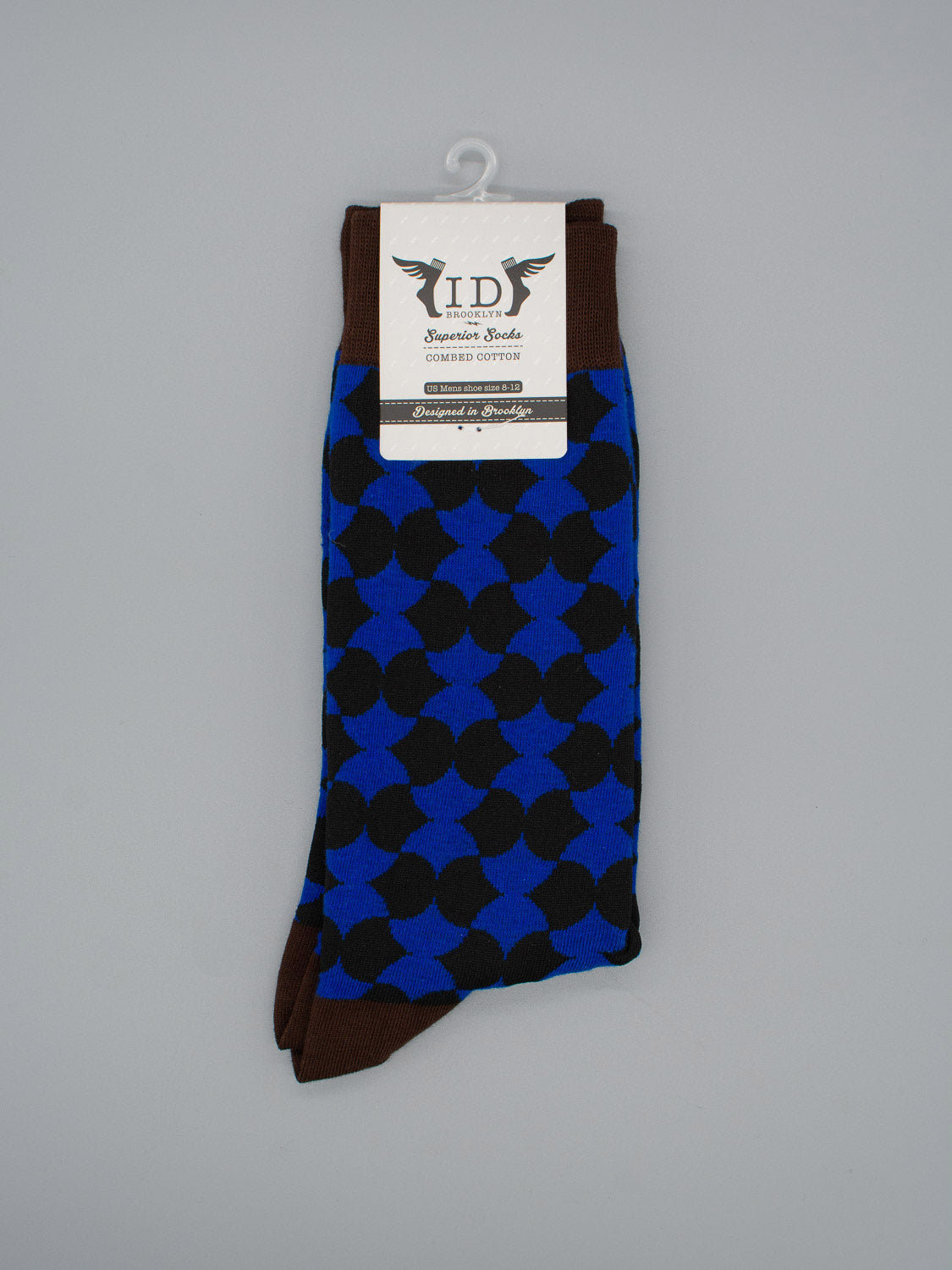 A pair of Wiggle Graphic Socks by ID Menswear, featuring a blue base with black circular patterns and brown toes, heels, and cuffs. Made from high-quality combed cotton, shown folded with a branded black-and-white label attached.