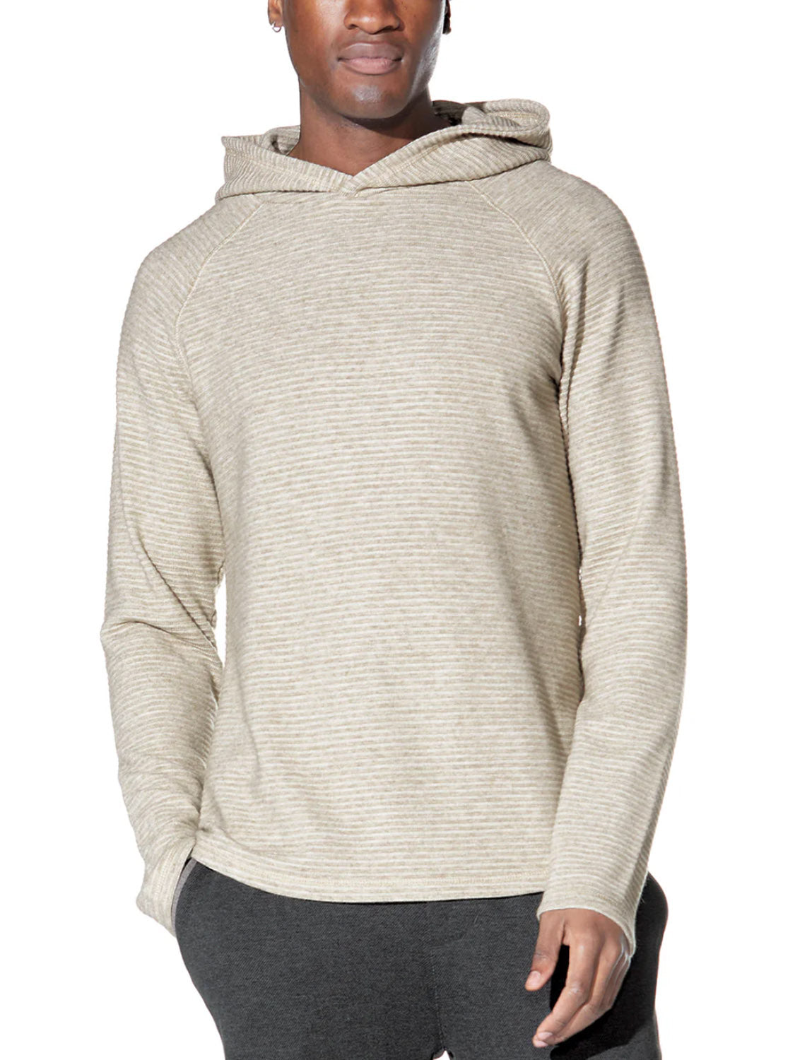 A person stands facing forward against a white background, wearing the Civil Society Wolfe Waffle Knit Hoodie—a light beige, subtly striped pullover with long sleeves—paired with dark pants, one hand in their pocket.