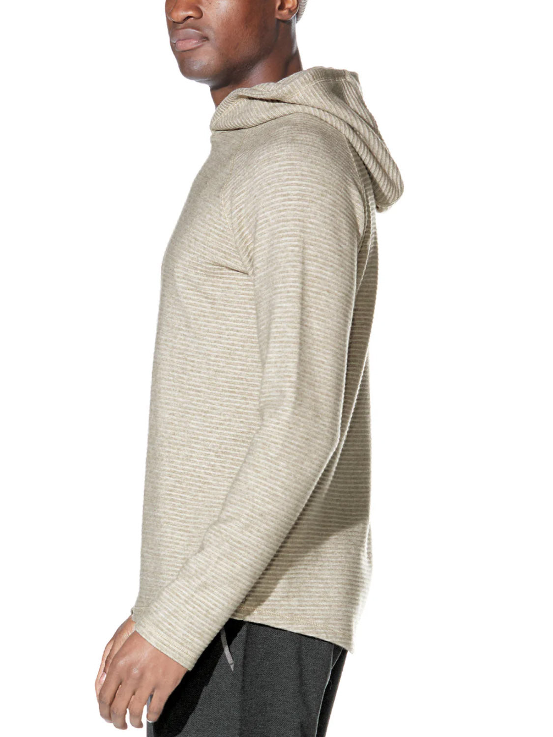 A man stands sideways against a white background, wearing the Civil Society Wolfe Waffle Knit Hoodie—a light beige, long-sleeve pullover featuring subtle horizontal stripes.