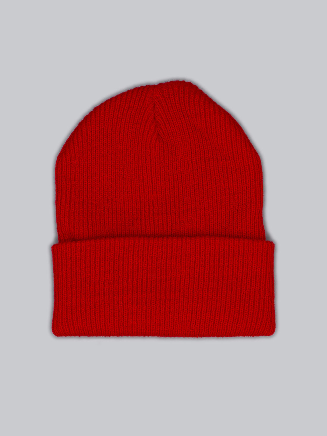 The Yonker Ribbed Acrylic Beanie by ID Menswear, in bright red with a folded brim, lies flat against a plain gray background. Its acrylic material showcases textured ribbed knitting for a classic fisherman style.
