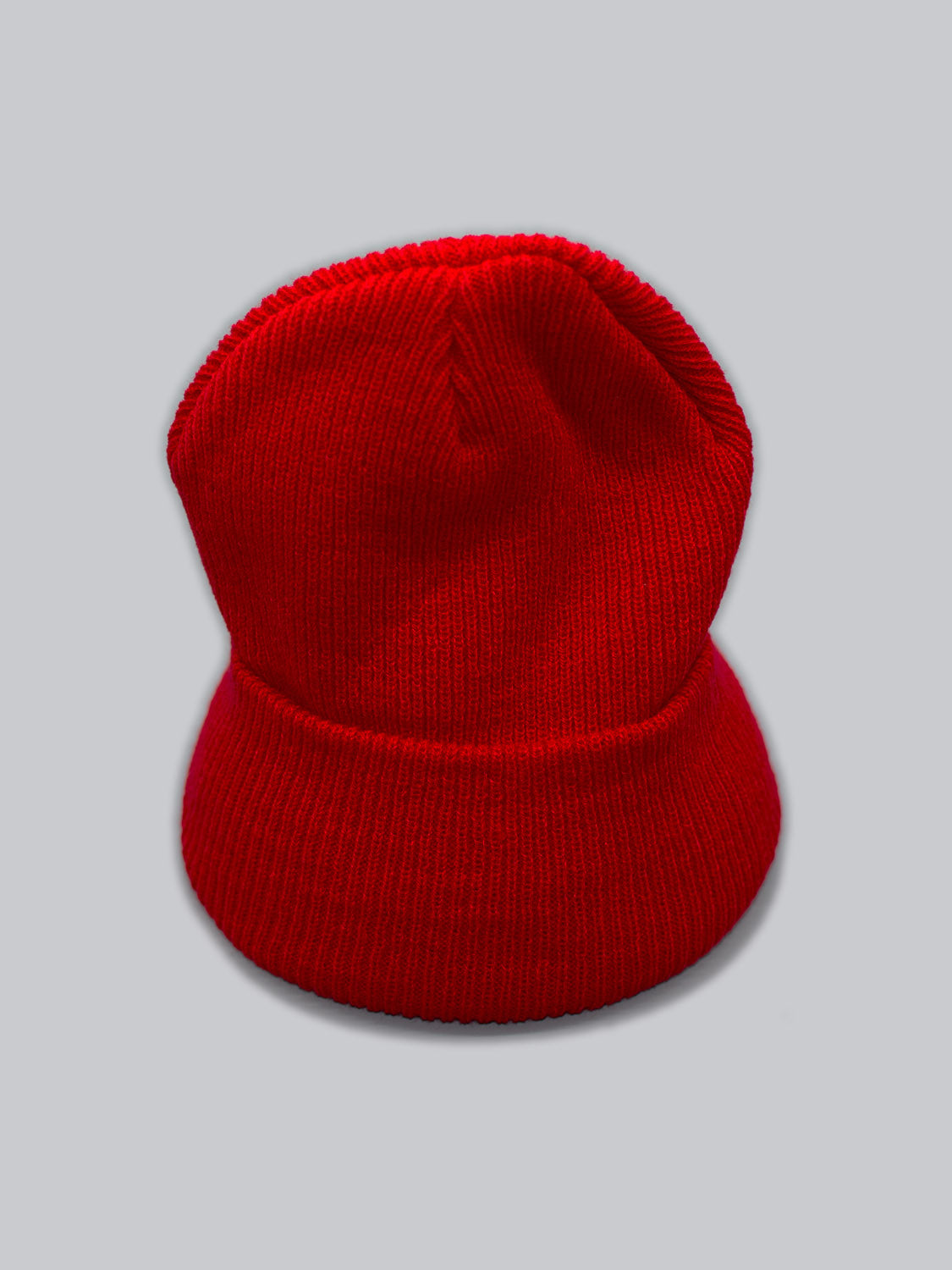 The Yonker Ribbed Acrylic Beanie by ID Menswear features a striking red rib-knit design with a folded brim, crafted from durable acrylic, set against a plain gray background.