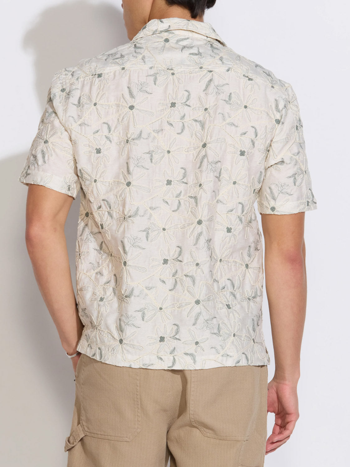 A person is shown from the back with hands partly in pockets, wearing the Civil Society Zanzibar Embroidered Appliqué Resort Shirt and beige cargo shorts.