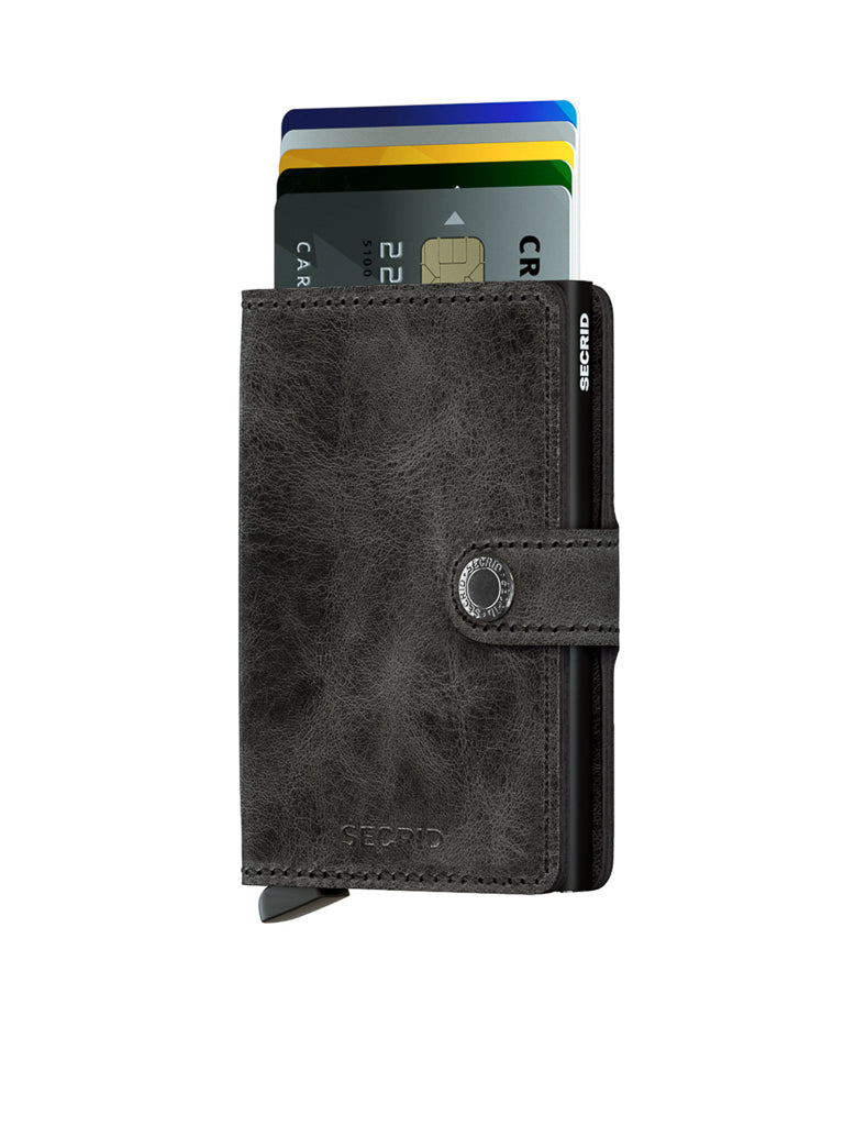 A partially open Secrid Miniwallet Vintage Leather in black with a button clasp displays four colorful cards inside. This RFID wallet is shown on a white background.