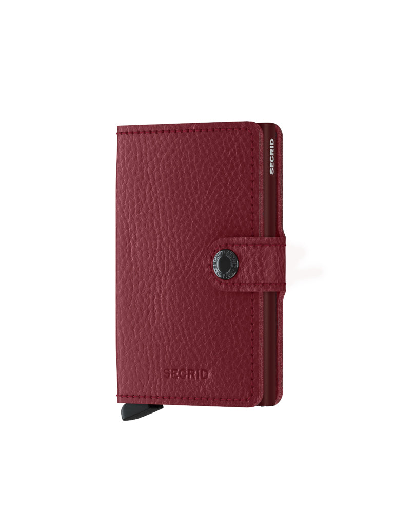 The Secrid Miniwallet Vegetable Tanned Leather is a compact red wallet with a textured finish, black button closure, RFID protection, and SECRID branding embossed on the front and side.