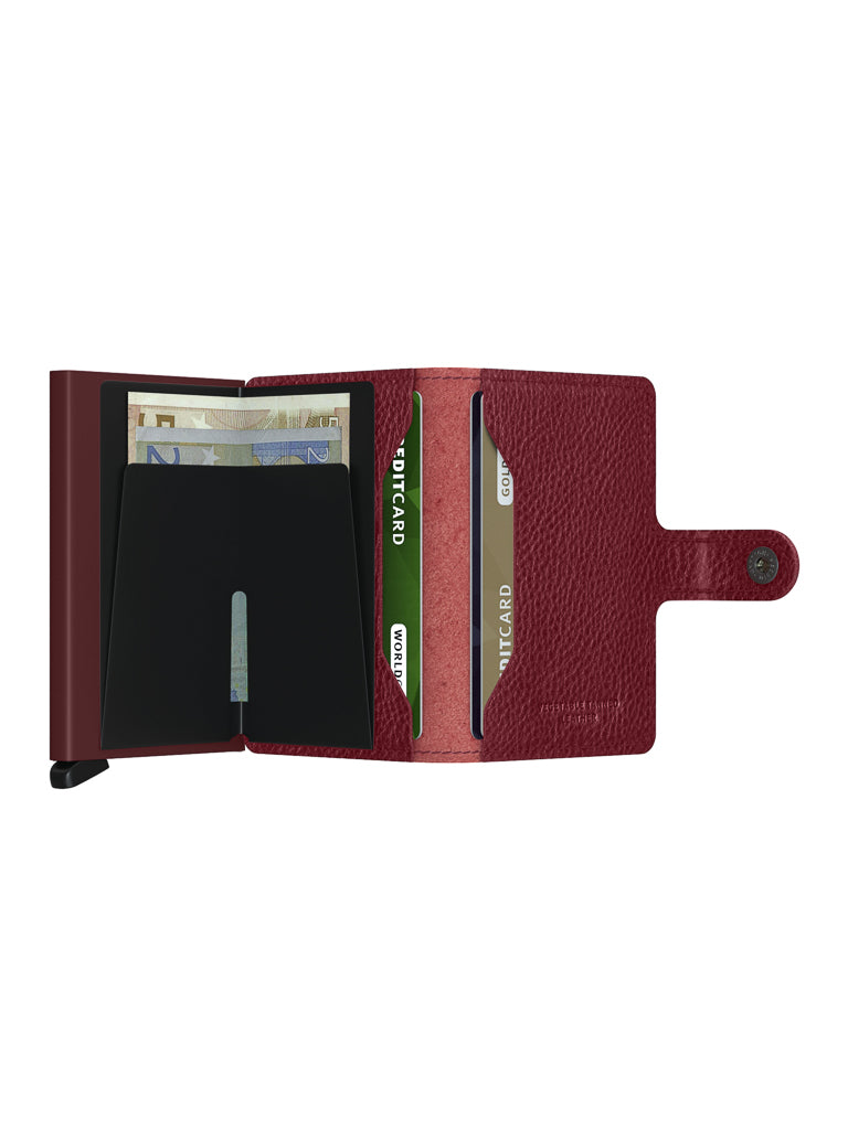 The Secrid Miniwallet Vegetable Tanned Leather in maroon features RFID-protected card slots and euro banknote storage, all secured by a side buttoned strap.