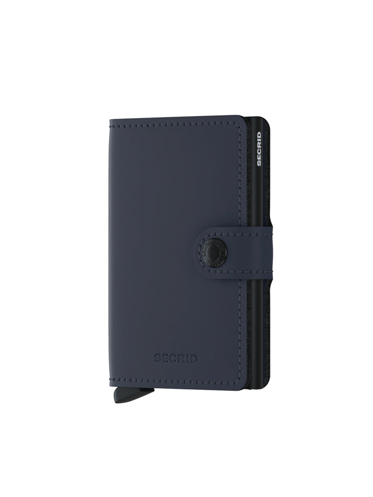 A Secrid Miniwallet Matte Finish Leather in navy blue, featuring a button snap closure and RFID protection, stands upright on a white background with its black card holder visible on the side.