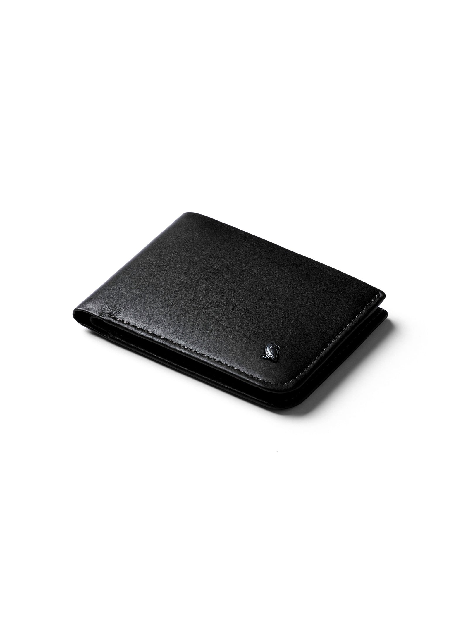 The Bellroy Hide and Seek Low Wallet, crafted from eco-tanned black leather with a discreet embossed logo in the bottom right corner, lies closed on a white surface. Its minimalist design and RFID protection ensure your personal data stays secure.