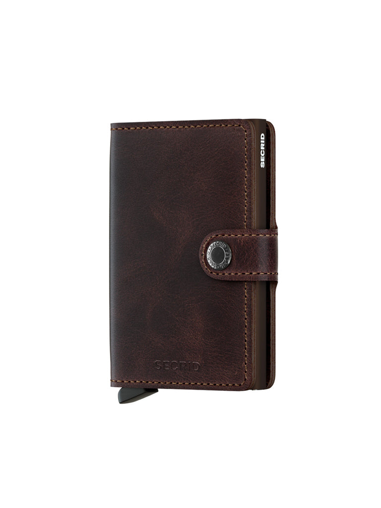 The Secrid Miniwallet Vintage Leather, in dark brown with a snap button closure and side branding, is pictured on a plain white background.