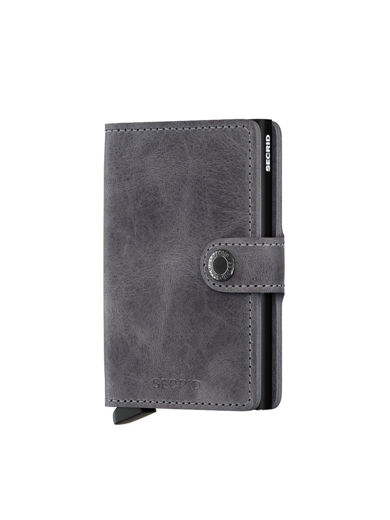 The Secrid Miniwallet Vintage Leather in gray features RFID protection, a buttoned strap closure, and visible side card slots, shown against a white background.