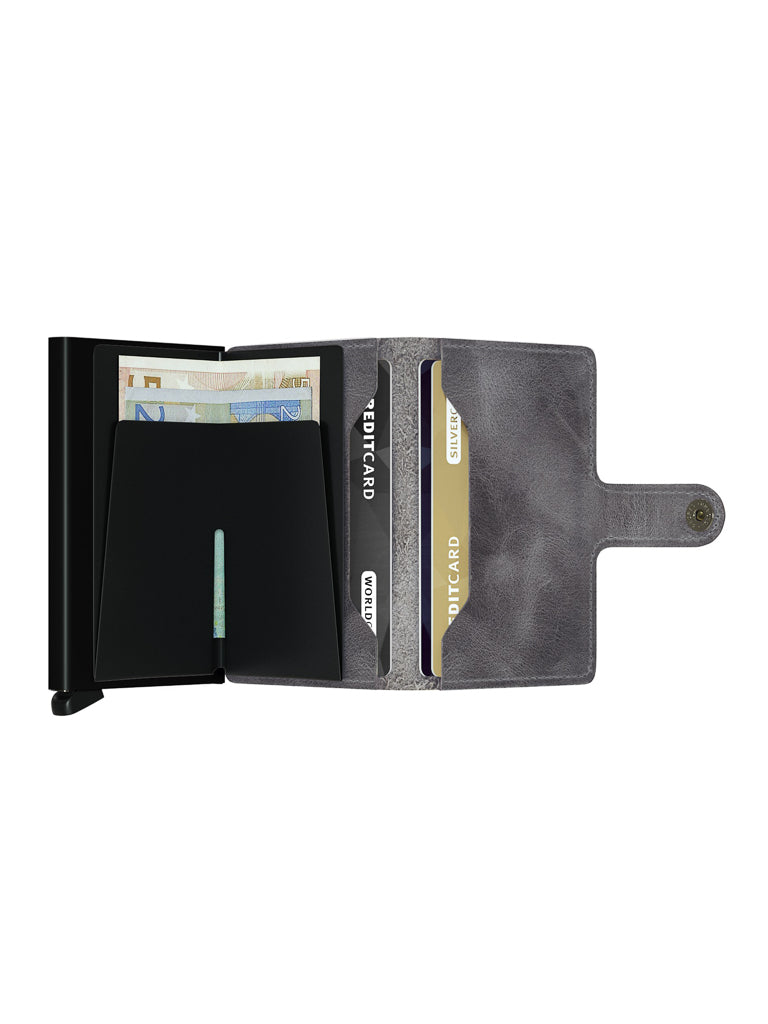 The Secrid Miniwallet Vintage Leather, shown in gray, is open to reveal compartments holding euro bills and cards, including two marked DUTCH CARD. It features RFID protection and a snap closure on the right side.