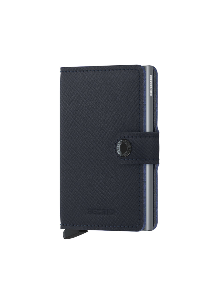 The Secrid Miniwallet Saffiano Leather is a compact, dark blue wallet with textured leather, RFID protection, snap button closure, and a metallic cardholder edge visible on the right.