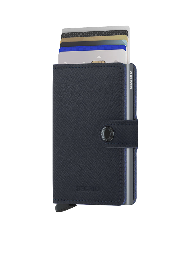 The Secrid Miniwallet Saffiano Leather in navy blue features RFID protection, a snap button closure, and embossed branding, and is shown partially open to display multiple cards inside.