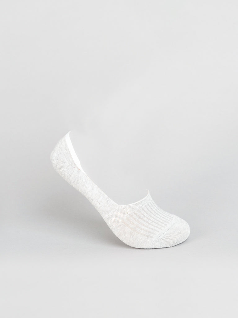 A single No Show Low Lightweight Sock by ID Menswear, made from breathable combed cotton, balances on its heel against a plain gray background, showcasing subtle ribbed detailing near the opening.