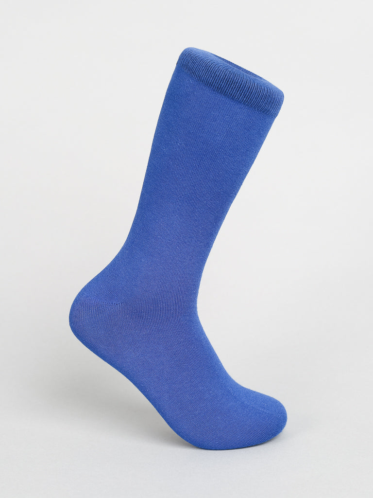 A Solid Color Combed Cotton Sock by ID Menswear is upright against a neutral backdrop. The blue sock, featuring a ribbed cuff, is crafted from combed cotton for comfortable daily wear and looks freshly laundered and neatly shaped.
