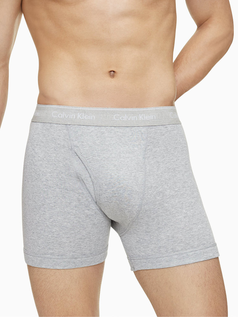 A person models light gray Calvin Klein NB4003 3-Pack Cotton Classic Boxer Briefs, shown from mid-torso to mid-thigh against a plain white background.