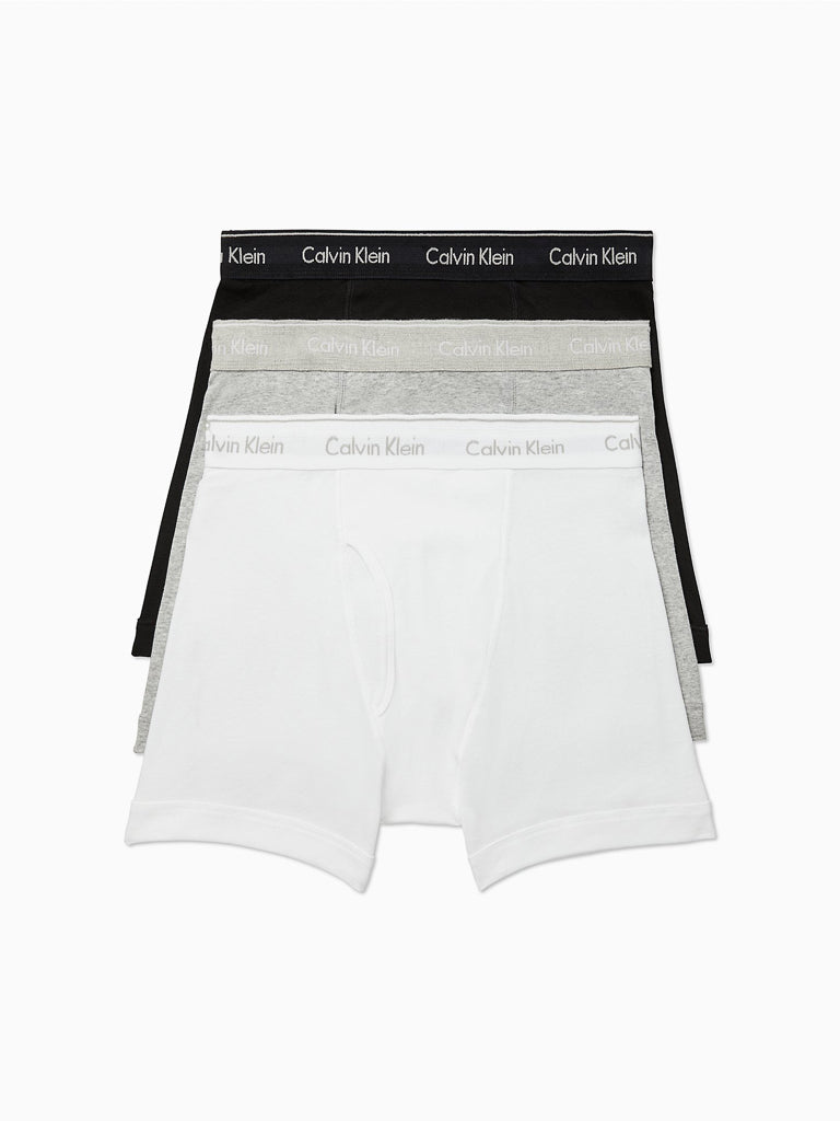 The Calvin Klein NB4003 3-Pack Cotton Classic Boxer Brief set includes black, gray, and white pairs. Each pure cotton trunk features an elastic waistband with the iconic Calvin Klein logo.