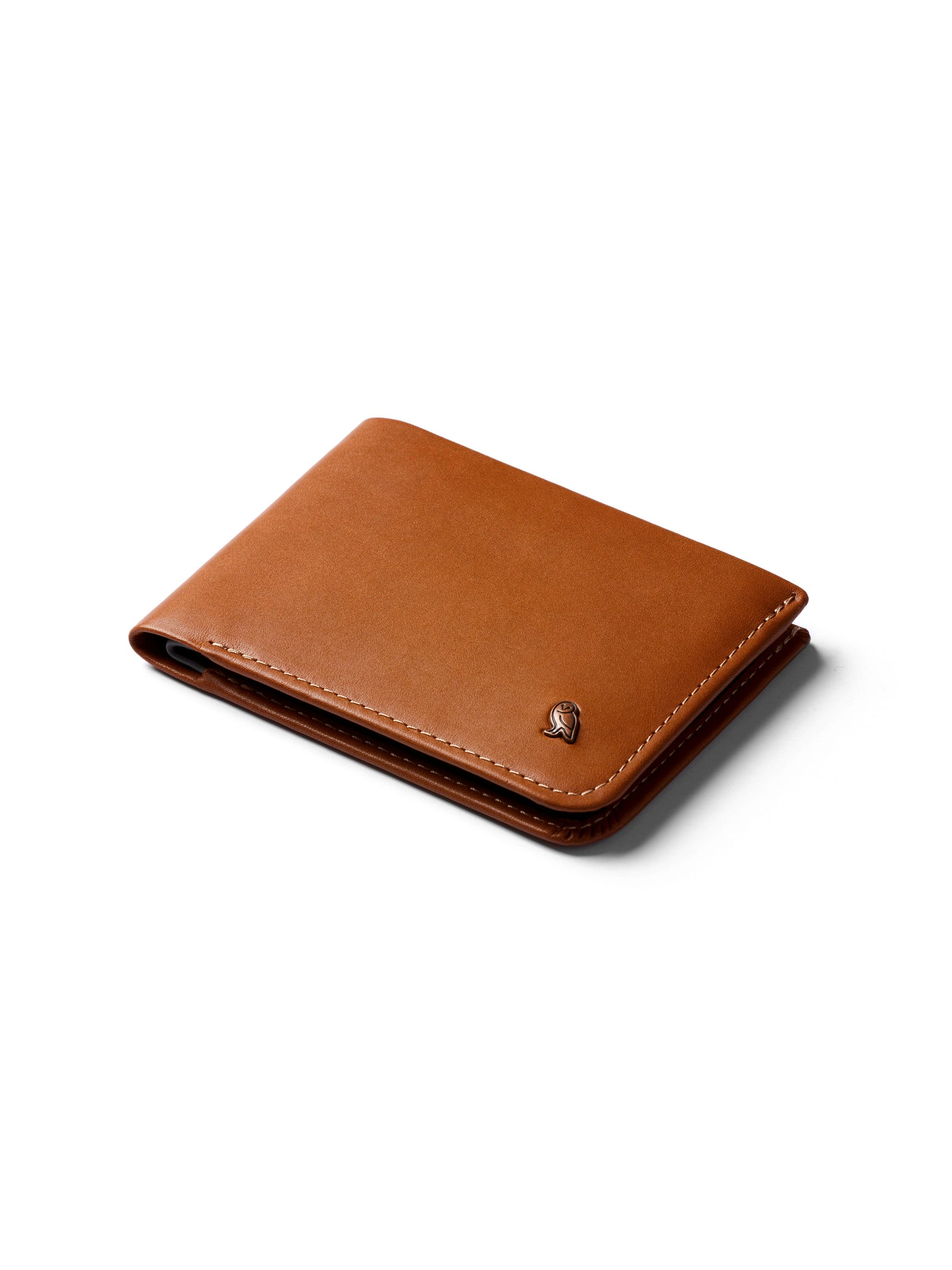 The Bellroy Hide and Seek Low Wallet is a brown eco-tanned leather bi-fold with visible stitching, RFID protection, a small metallic emblem on the bottom right, and a hidden coin pouch, shown on a white background.