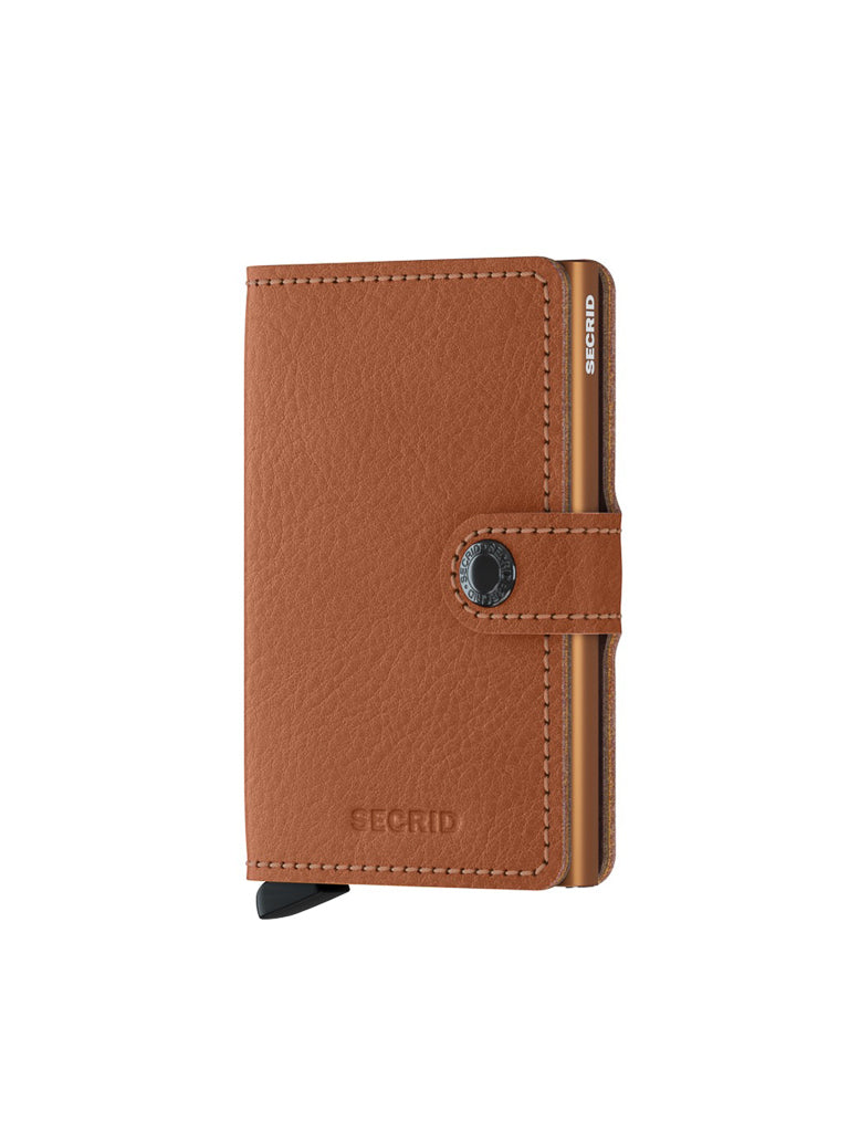 A Secrid Miniwallet Vegetable Tanned Leather in brown features RFID protection, a snap button closure, a card slider mechanism, and stands upright on a white background, highlighting its compact design.