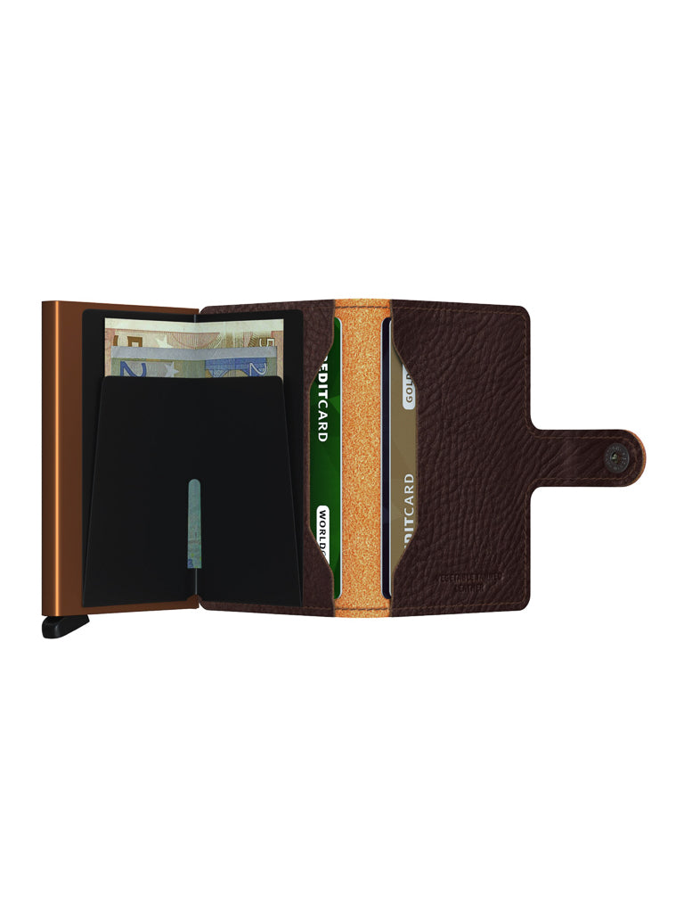 The Secrid Miniwallet Vegetable Tanned Leather in brown opens to show euro notes and cards organized in slots, featuring RFID protection and a buttoned strap on the right.