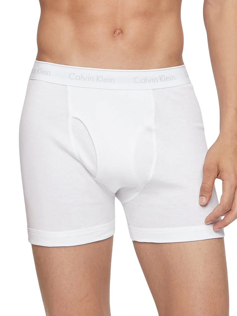 A person wearing white Calvin Klein NB4003 3-Pack Cotton Classic Boxer Briefs, shown from mid-torso to mid-thigh against a plain background. The waistband displays the Calvin Klein logo, highlighting the classic boxer brief fit.