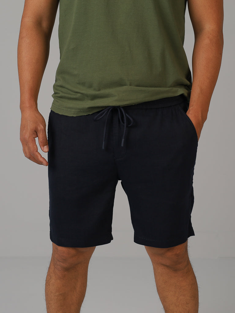Someone wearing a green T-shirt and Driggs Linen Blend Short by ID Menswear stands against a plain background. The photo, cropped at the shoulders, highlights this casual and comfortable outfit ideal for warm weather.
