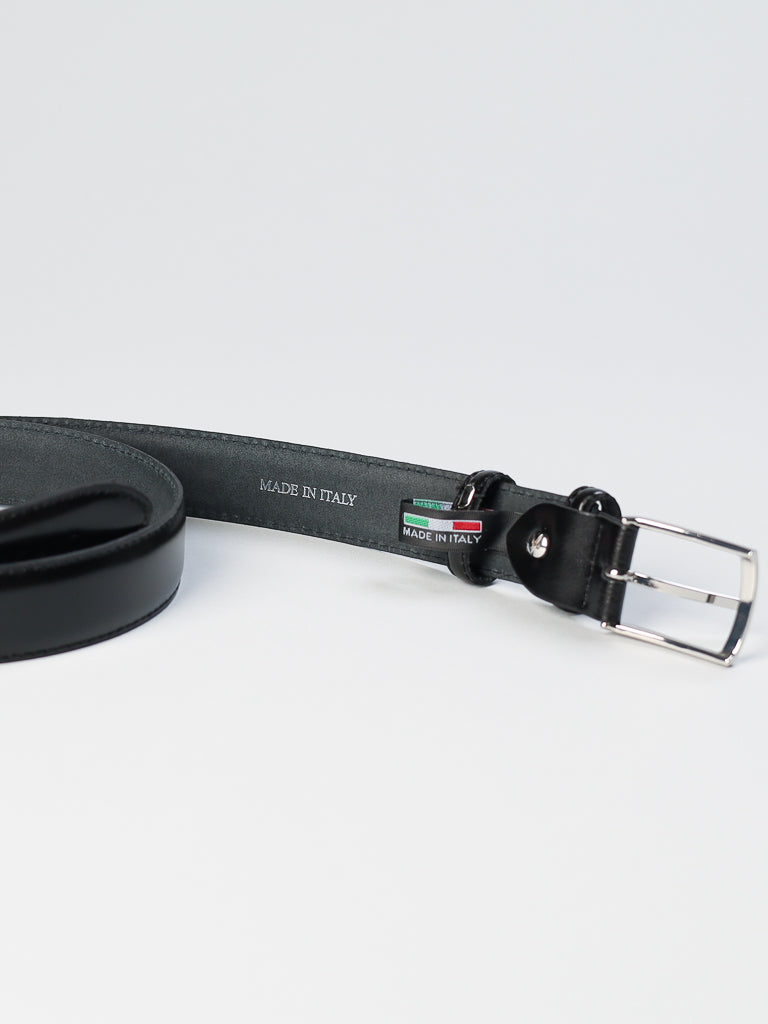 The ID Menswear 4904 Made in Italy Leather Belt lies on a white surface, featuring a solid metal buckle. Inside, Made in Italy is embossed, and small Italian flag-themed tags adorn the area near the buckle.