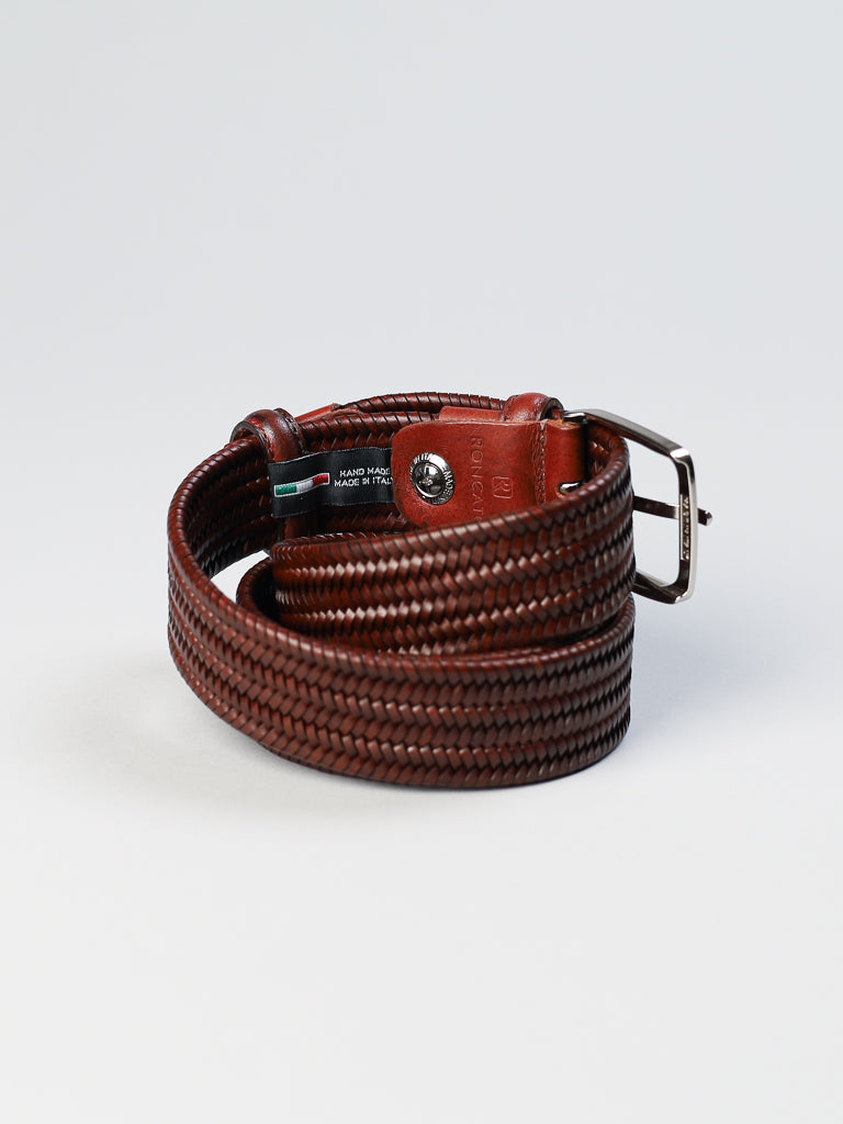 The ID Menswear 4553 Made in Italy Braided Leather Belt, crafted from genuine brown leather, features a silver buckle and rests gracefully against a plain light gray background.