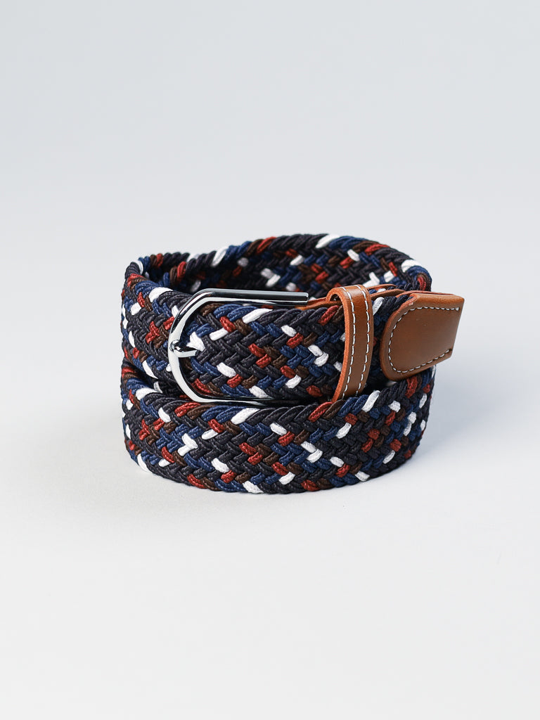 The ID Menswear ID Braided Stretch Woven Belt features a navy, white, and rust braided pattern with brown leather accents and a metal buckle, displayed artfully rolled on a light gray background.