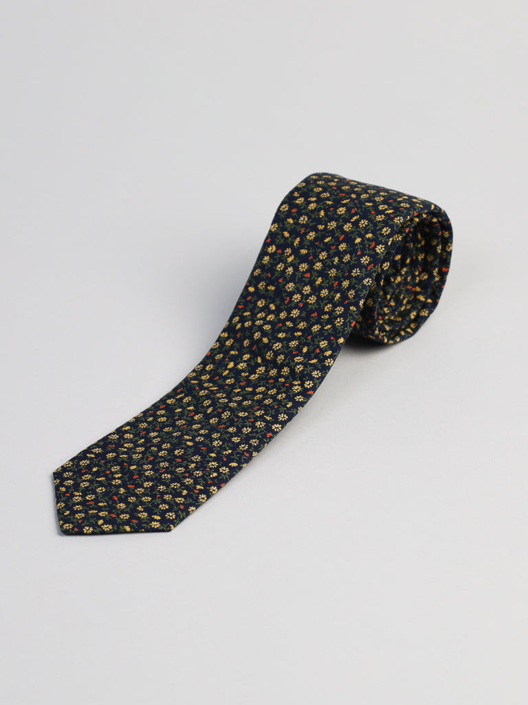 The Japanese Printed Hana NYGR Tie by ID Menswear features a dark print with yellow and red floral patterns, handmade in Brooklyn from 100% cotton, shown on a plain light background.