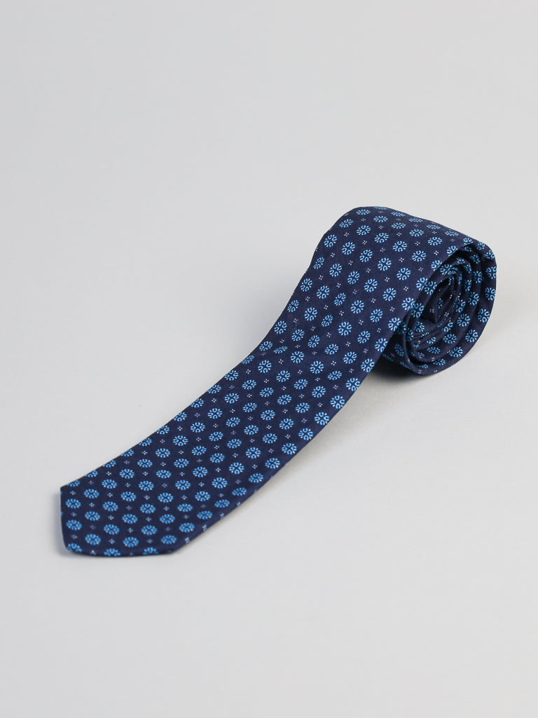 The Play Day Cotton Tie by ID Menswear is a navy blue, handmade cotton tie with small light blue geometric shapes, shown on a light gray background—ideal for business formal occasions.